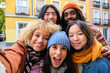 © Ladanifer - Multiracial friends group taking selfie pic with smartphone outside in autumn. Happy young people having fun walking on city street. Friendship concept with guys and girls enjoying outside.