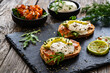 Tasty sandwiches - toasted bread with burrata cheese, smoked salmon, avocado and arugula on wooden table

