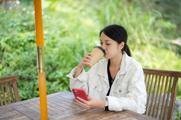 Sticker - Woman drink of coffee and use smart phone at outdoor coffee shop