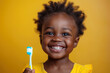 happy smile black kid child holds a toothbrush in hand on an yellow isolated background. Pediatric dentistry for brushing teeth