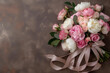 Bouquet of pink and white roses, peonies with pastel colored ribbon on a  beige background in a top view. Greeting card for Mother's Day, birthday or Valentine's Day or wedding