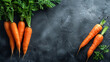 Fresh carrots with green tops on a dark, textured background with copy space.