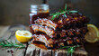 Stacked artisanal BBQ ribs glistening with a sticky glaze, accented by a halved lemon and fresh green rosemary on a weathered wood backdrop.
