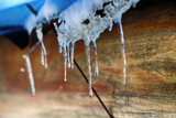 Fototapeta  - Sopel. Topniejące sople lodowe na zadaszeniu budynku zimą