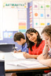 © Austockphoto - Happy student looking at the camera whilst her classmates concentrate