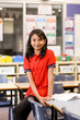 © Austockphoto - Female student sitting on a desk in a classroom smiling