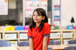 © Austockphoto - Female school student in a red polo shirt thoughtfully standing in classroom