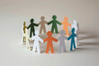 © Jameel - White paper figures of people standing in a circle, holding hands, on a neutral background