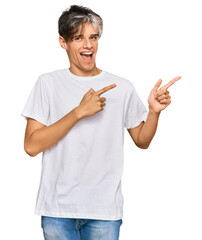 Wall Mural - Young hispanic man wearing casual white tshirt smiling and looking at the camera pointing with two hands and fingers to the side.