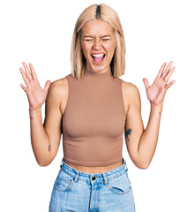 Wall Mural - Beautiful young blonde woman wearing casual style with sleeveless shirt celebrating mad and crazy for success with arms raised and closed eyes screaming excited. winner concept