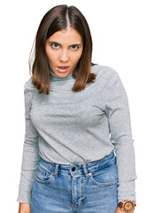 Canvas Print - Young beautiful woman wearing casual turtleneck sweater in shock face, looking skeptical and sarcastic, surprised with open mouth