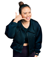 Sticker - Young hispanic girl wearing sportswear smiling doing phone gesture with hand and fingers like talking on the telephone. communicating concepts.