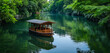 A peaceful little houseboat surrounded by lush vegetation and floating idly down a calm river