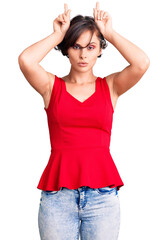 Poster - Beautiful young woman with short hair wearing casual style with sleeveless shirt doing funny gesture with finger over head as bull horns