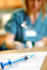 Close-up of a syringe and a doctor in the background
