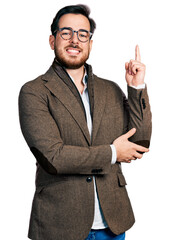 Wall Mural - Young hispanic man wearing business jacket and glasses with a big smile on face, pointing with hand and finger to the side looking at the camera.