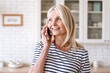© brizmaker - Middle aged woman entrepreneur working at home and talking on smartphone