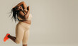 © gstockstudio - Full length happy plus size African woman in sportswear dancing on studio background