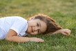 © Irina Mikhailichenko - Happy little girl lying on grass and smiling. Perfect for innocence and joy of childhood concept. Ideal for use in advertisements, blog or any content related to children, nature. High quality photo