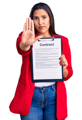 Canvas Print - Young beautiful brunette woman holding clipboard with contract with open hand doing stop sign with serious and confident expression, defense gesture