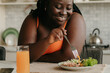 © gstockstudio - Beautiful curvy African woman enjoying healthy eating for lunch at home