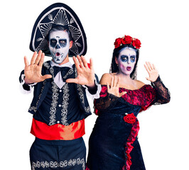 Canvas Print - Young couple wearing mexican day of the dead costume over background doing stop gesture with hands palms, angry and frustration expression