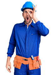 Canvas Print - Young handsome man wearing worker uniform and hardhat pointing down with fingers showing advertisement, surprised face and open mouth