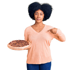 Poster - Young african american girl holding italian pizza pointing finger to one self smiling happy and proud