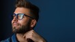 © Vlad - Elegant  man with beard wearing glasses smiling in a blue shirt against a dark background.