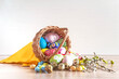 Easter holiday greeting card; Wicker basket with various easter eggs, willow twigs on a wooden background