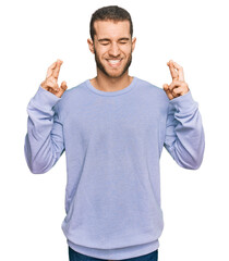 Wall Mural - Young caucasian man wearing casual clothes gesturing finger crossed smiling with hope and eyes closed. luck and superstitious concept.