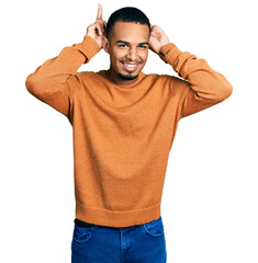 Poster - Young african american man wearing casual clothes posing funny and crazy with fingers on head as bunny ears, smiling cheerful