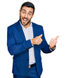 © Krakenimages.com - Young hispanic man wearing business jacket pointing to the back behind with hand and thumbs up, smiling confident