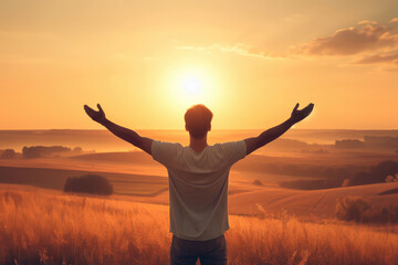 man is standing in field with his arms raised, looking up at sun