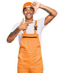 Poster - Young handsome african american man wearing handyman uniform smiling making frame with hands and fingers with happy face. creativity and photography concept.