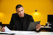 © Svitlana - Joyful young male employee sitting and looking at tablet