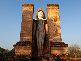 Ancient standing Buddha statue. Wat Mahathat at sunset. Sukhothai Historical Park. Thailand.