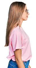 Wall Mural - Hispanic young woman wearing casual t shirt and glasses looking to side, relax profile pose with natural face with confident smile.