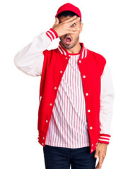 Canvas Print - Young hispanic man wearing baseball uniform peeking in shock covering face and eyes with hand, looking through fingers with embarrassed expression.