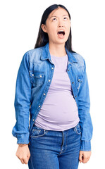 Poster - Young beautiful chinese woman pregnant expecting baby angry and mad screaming frustrated and furious, shouting with anger. rage and aggressive concept.