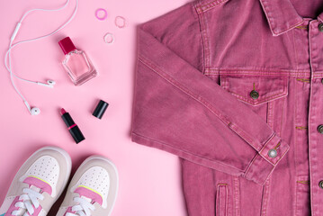 Wall Mural - Pink denim jacket with cosmetics on pink background. Top view point, flat lay.