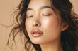 Asian woman with closed eyes on soft beige background highlighting natural make-up