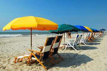 Beach umbrellas and beach chairs line the sandy shore on a summer vacation day in Myrtle Beach, South Carolina