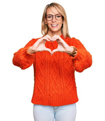 Wall Mural - Beautiful blonde woman wearing casual clothes and glasses smiling in love doing heart symbol shape with hands. romantic concept.