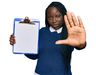 Poster - Young black woman with braids holding clipboard with blank space with open hand doing stop sign with serious and confident expression, defense gesture