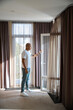 © Svitlana - Side of african american man closing door to balcony in hotel room at sunny day