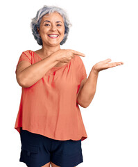 Poster - Senior woman with gray hair wearing orange tshirt amazed and smiling to the camera while presenting with hand and pointing with finger.