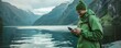 Hiker using smartphone by mountain lake. Outdoor adventure and technology concept