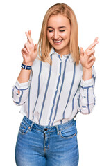 Wall Mural - Beautiful caucasian woman wearing casual clothes gesturing finger crossed smiling with hope and eyes closed. luck and superstitious concept.