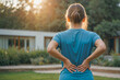 Woman suffer from low back pain standing in a yard. Hand of woman holding her waist backache in pain. Health care concept